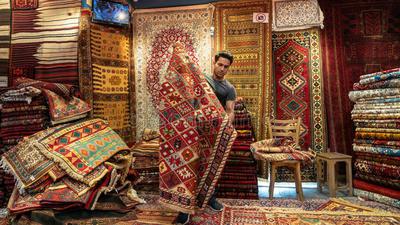 young-iranian-carpet-seller-presenting-persian-carpets-to-tourists-shop-isfihan-iran-may-161476611.jpeg